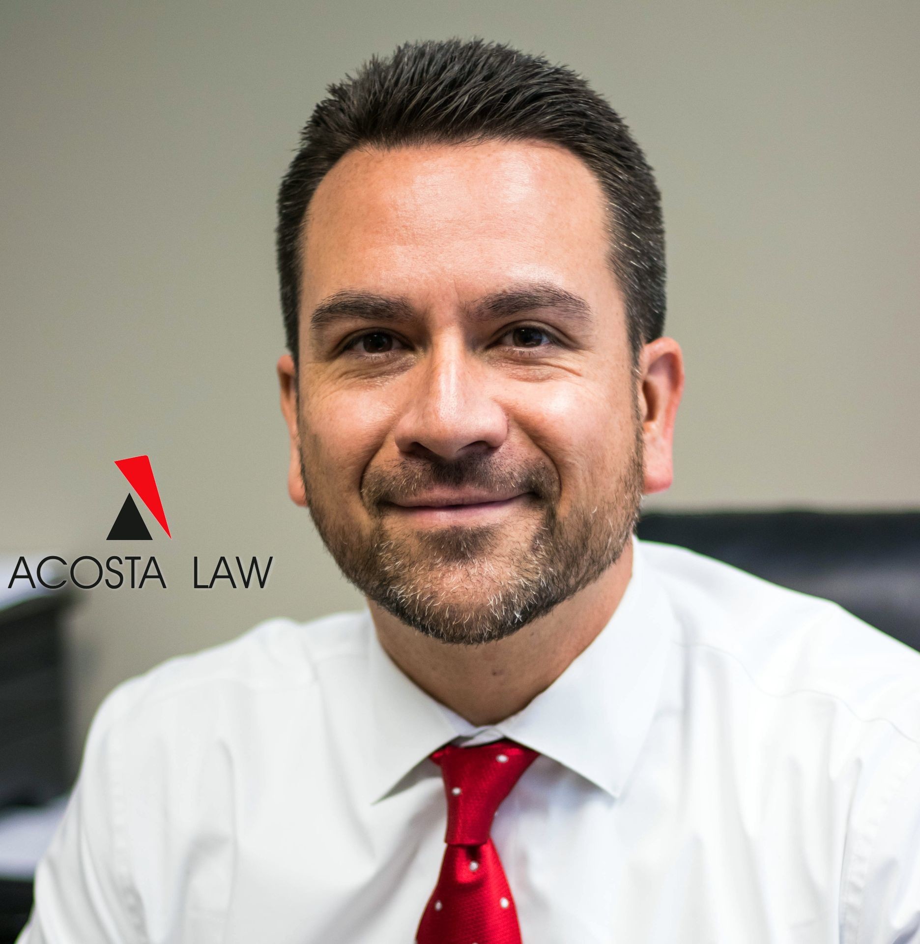 Man in a white shirt and red tie smiling beside Acosta Law logo.